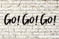 Ã¢â¬ÅGo! Go! Go!Ã¢â¬Â motivational text written on a white stone brick wall background